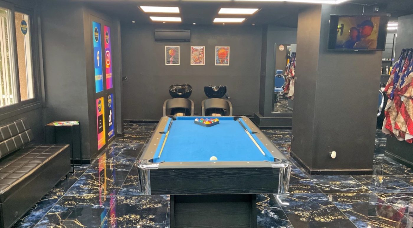 Espace détente de Barber Factory avec billard, banquette et sol en marbre noir, bleu et doré
